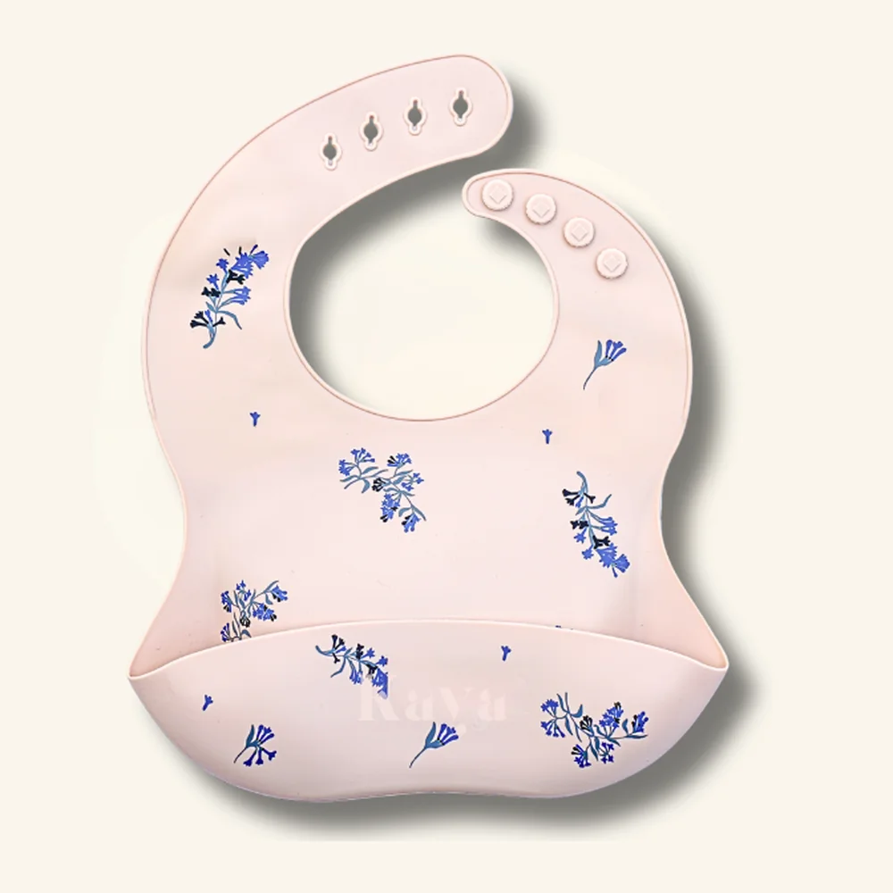 KAYA 2-pack of silicone baby bibs: a deep navy blue bib and a blush pink bib with a blue and lilac flower print, each with a food-catcher pocket and snap neck